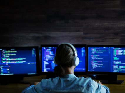 mulher com três monitores a programar