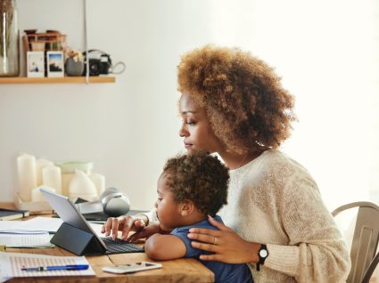 mãe com filho ao colo a pesquisar sobre a licença parental complementar