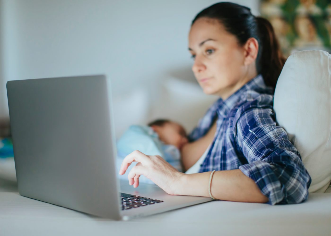 mãe a amamentar e a trabalhar ao computador