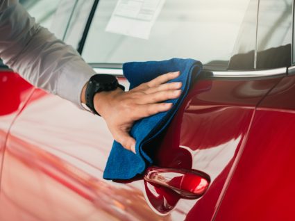 pessoa a passar pano para dar brilho ao carro