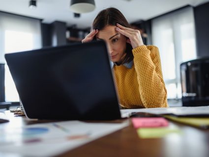 mulher com mãos na cabeça em frente ao computador