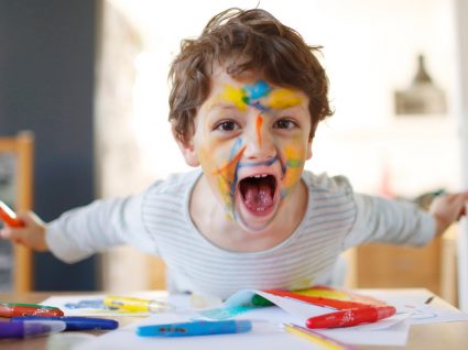 criança a gritar, com cara pintada e lápis de cor e folhas