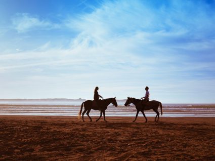 Casal a andar a cavalo na praia