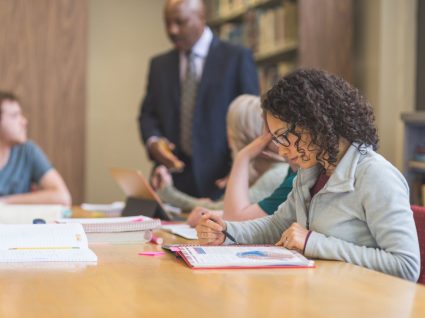 mulher em biblioteca a estudar para pós-graduação