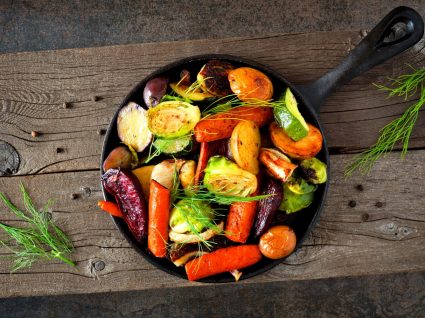 frigideira com legumes em cima de tábua de madeira