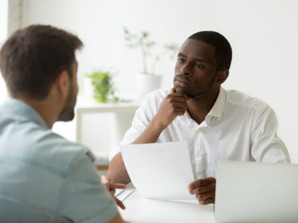 homem com ar sério a ouvir o que o outro tem para dizer