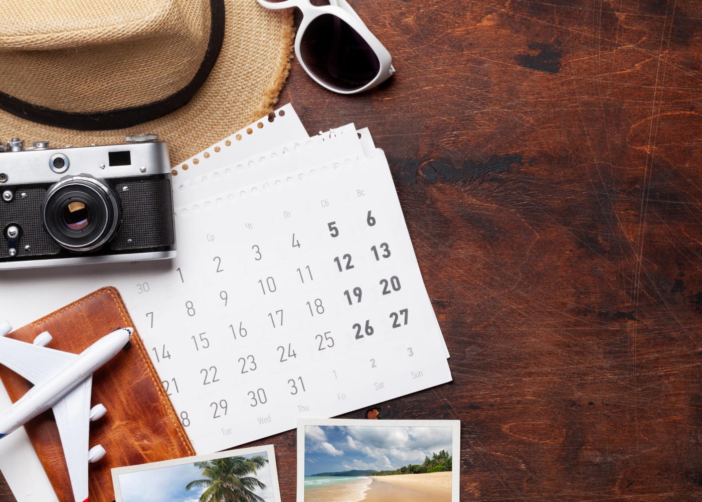 calendário, chapéu, avião e máquina fotográfica dispostos numa mesa