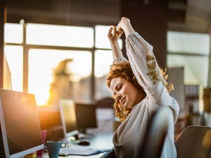 mulher em frente ao computador a fazer alongamentos como um dos exercícios para fazer no escritório