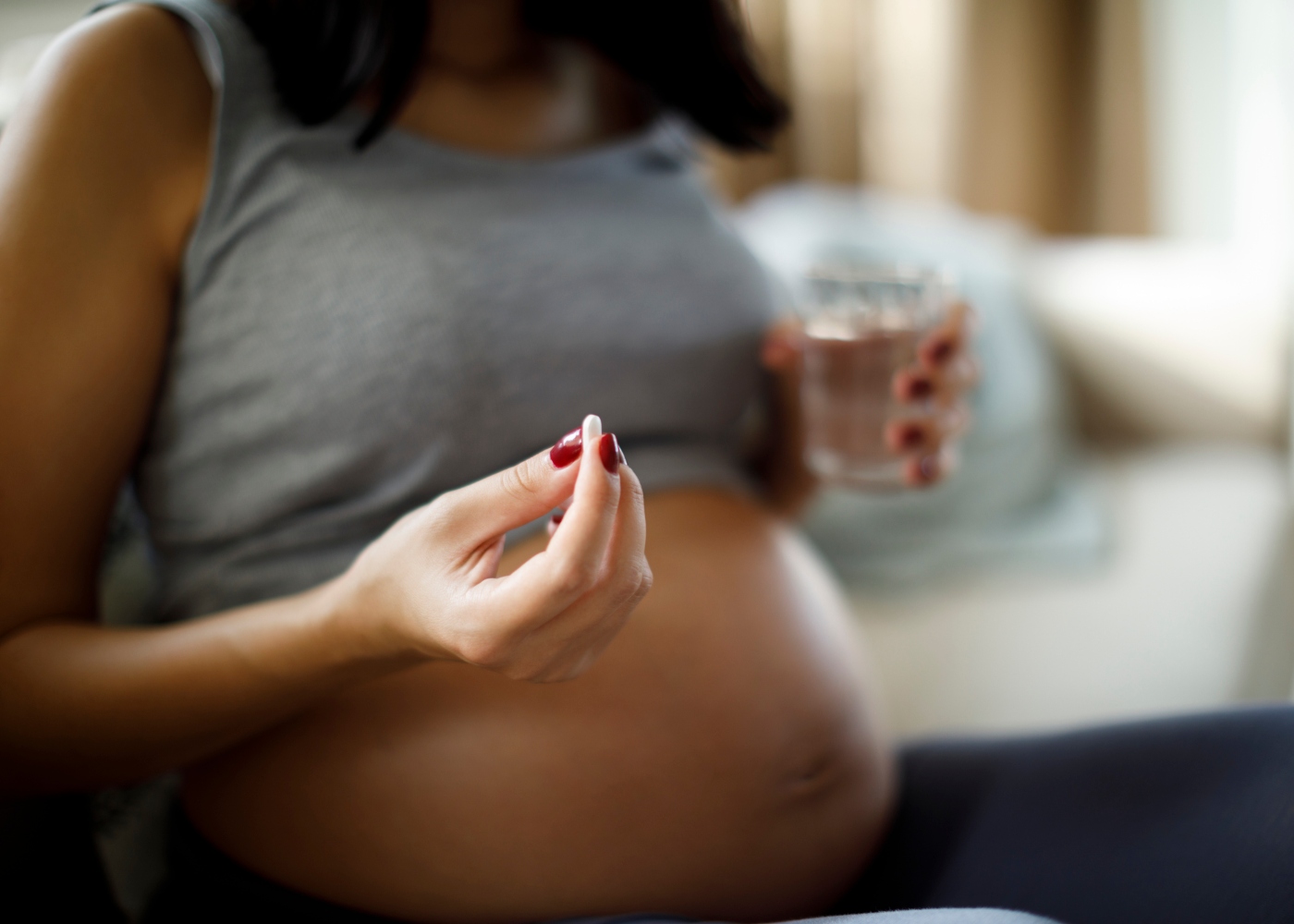 grávida com copo de água e comprimido na mão