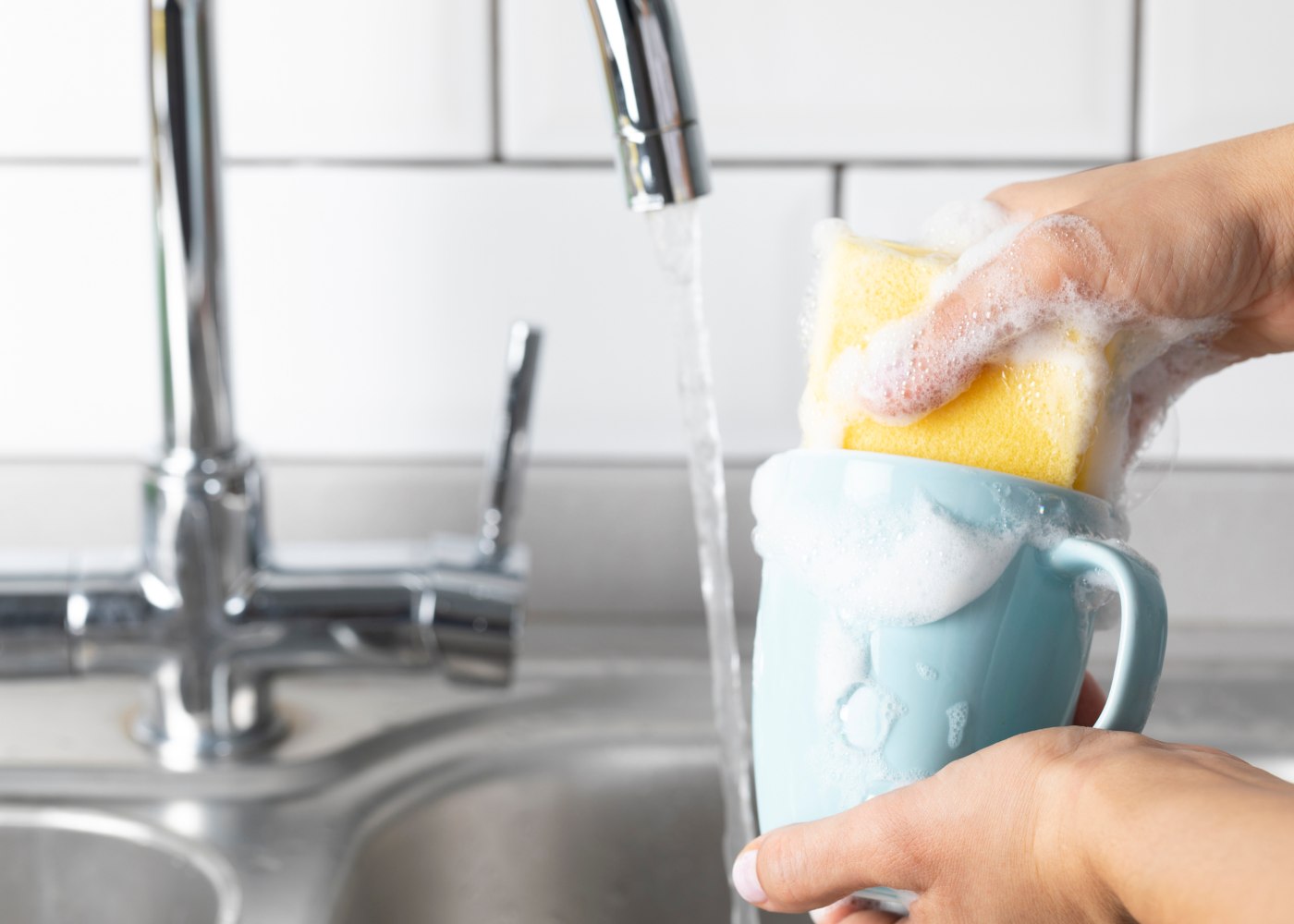 pessoa a lavar uma caneca e a ter em conta os erros a evitar a lavar a louça
