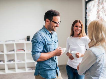 três colegas a conversar e a tomar café