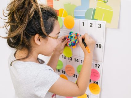 aluna a fazer anotações num calendário pendurado na parede