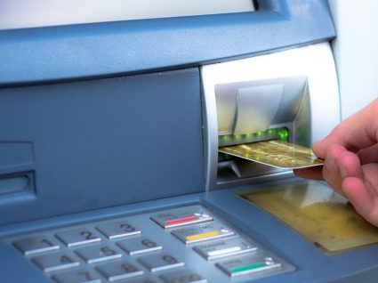 Homem a utilizar cartão de débito numa caixa Multibanco
