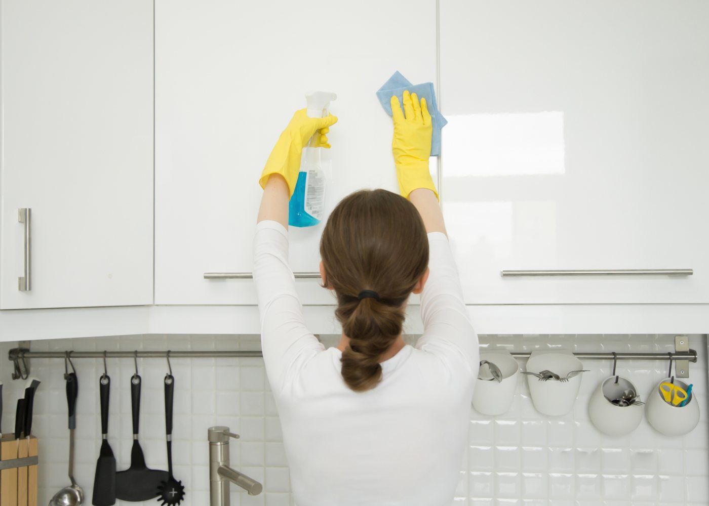 mulher a limpar os armários de cozinha