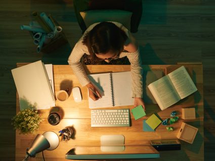 vista de cima de uma jovem a estudar e todo o material