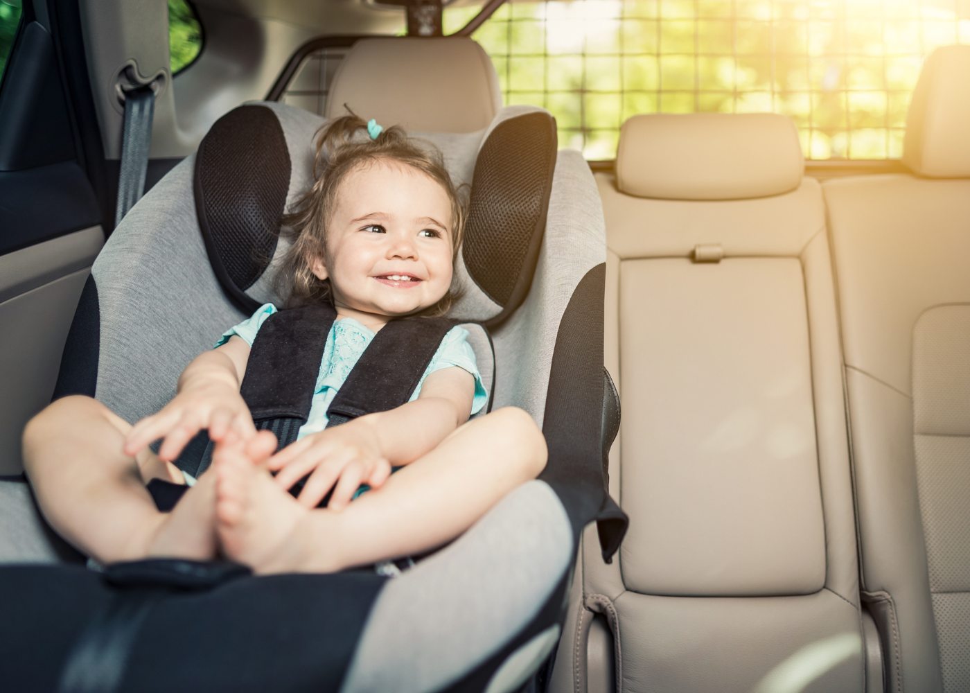 bebé a sorrir sentado na cadeirinha de um carro