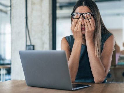 mulher ao computador com ar cansaço a analisar causas de stress no trabalho