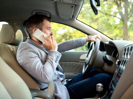 homem a falar ao telemovel enquanto conduz