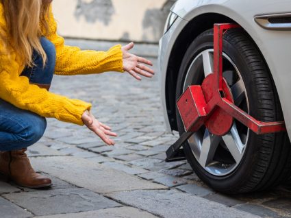 Mulher a olhar para carro com roda bloqueada