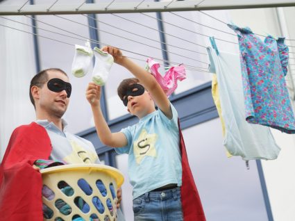 pai e filhos vestidos de super-herói a estender a roupa