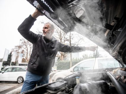 condutor com capot do carro aberto por motor em autocombustão