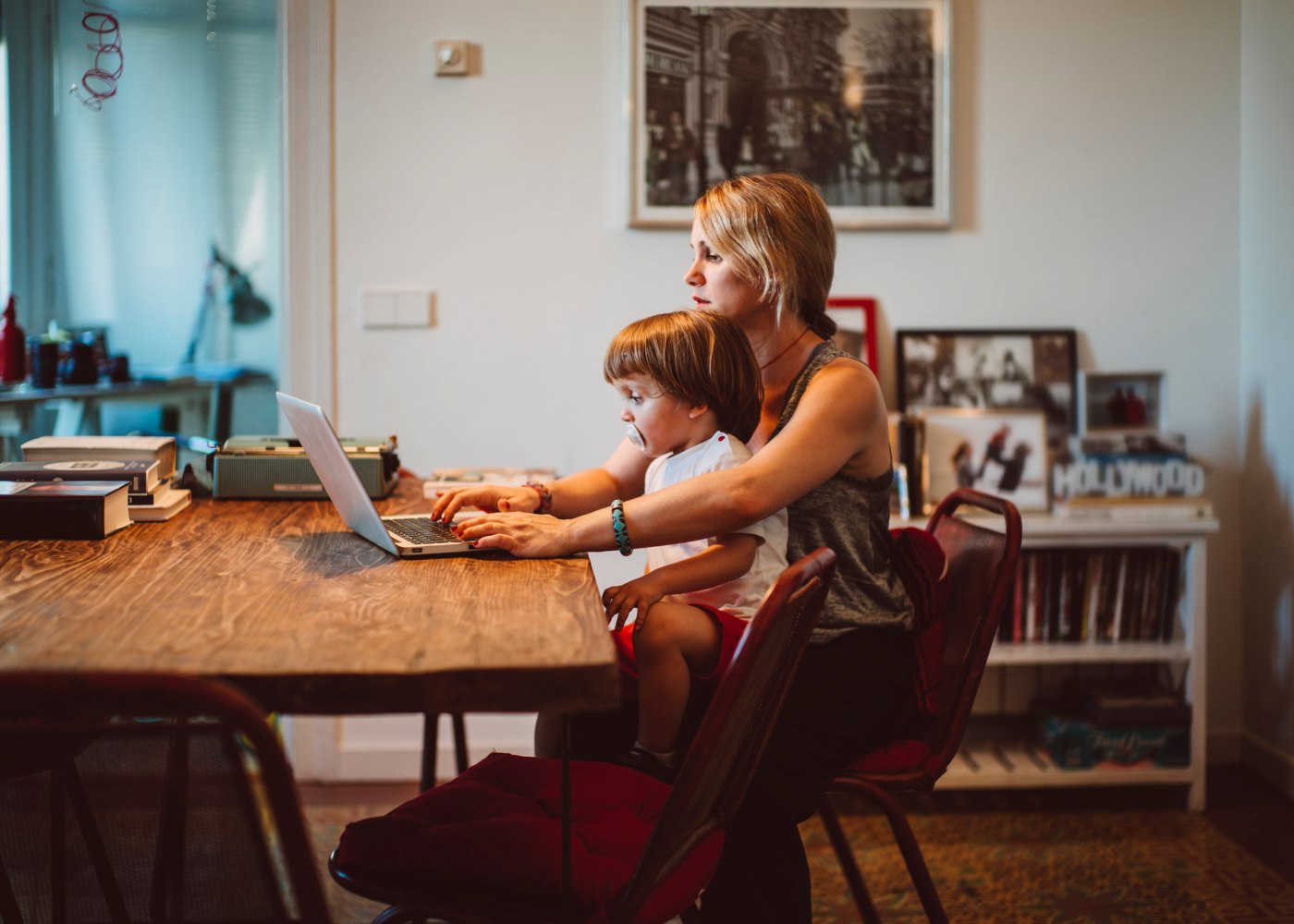 mãe a trabalhar ao computador com um filho ao colo