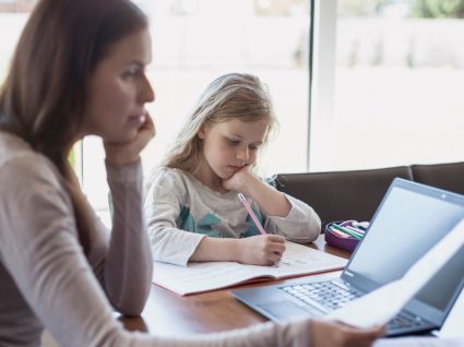 mãe a trabalhar em casa com filha a estudar ao lado