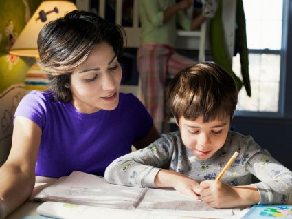 mãe a seguir indicações do guia para os pais e a ajudar o filho a estudar