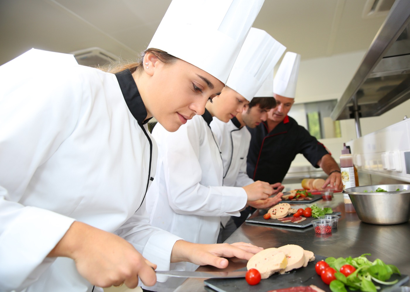 estagiários de cozinha a preparar prato com o orientador