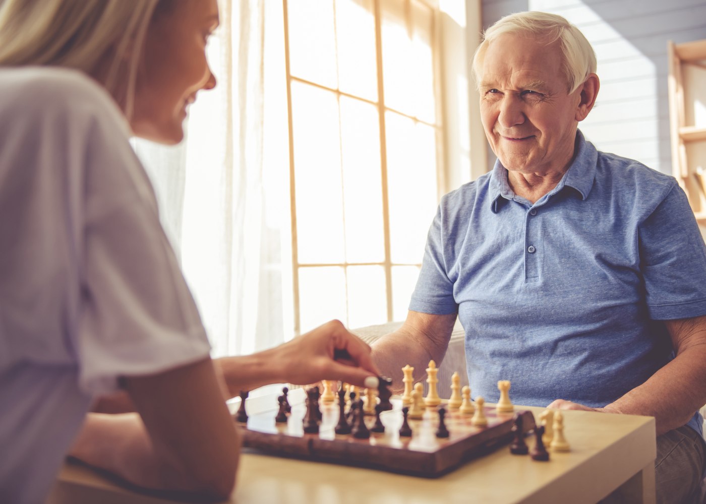 cuidadora a jogar xadrez com idoso