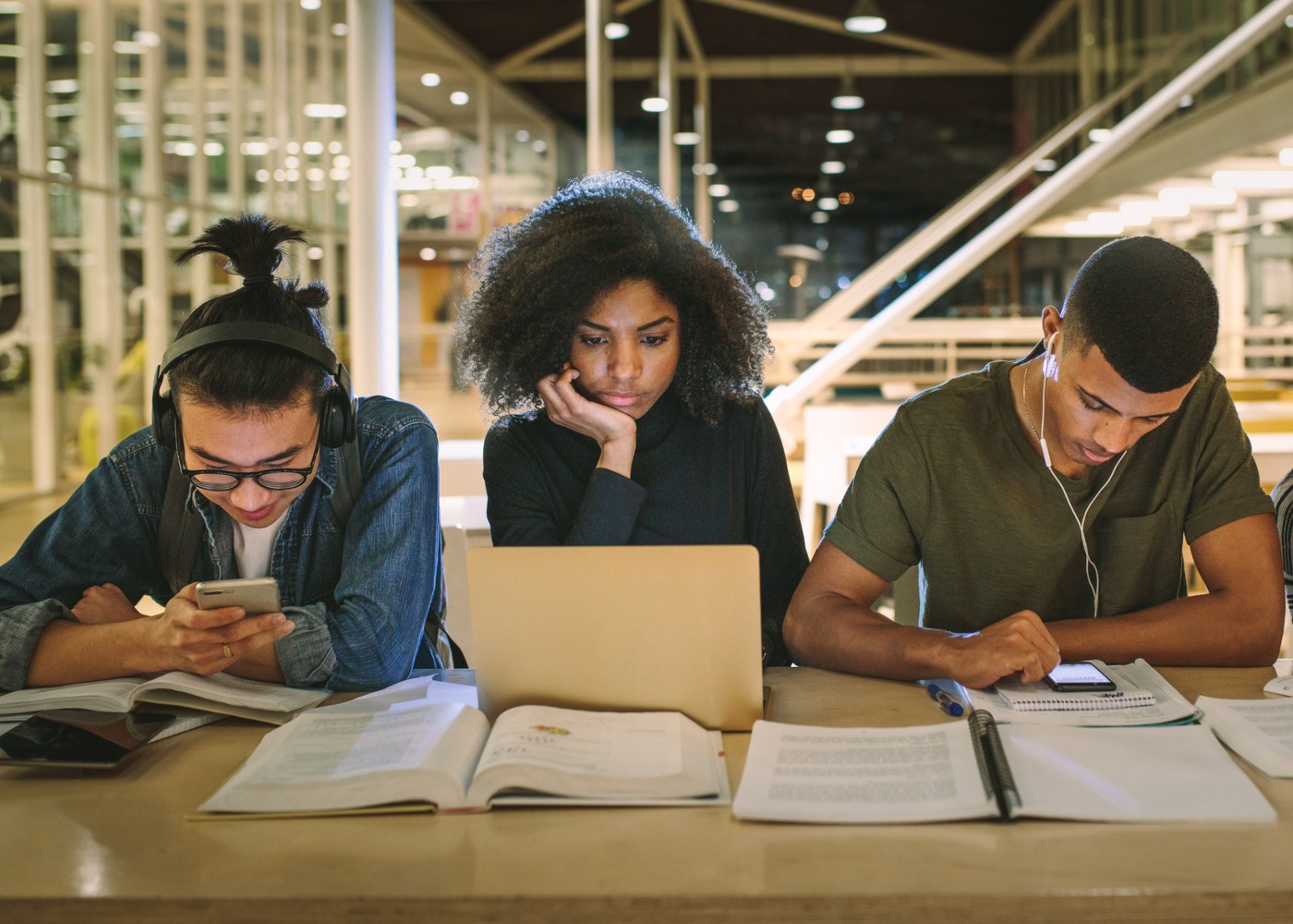 três jovens a estudar com cadernos e computadores