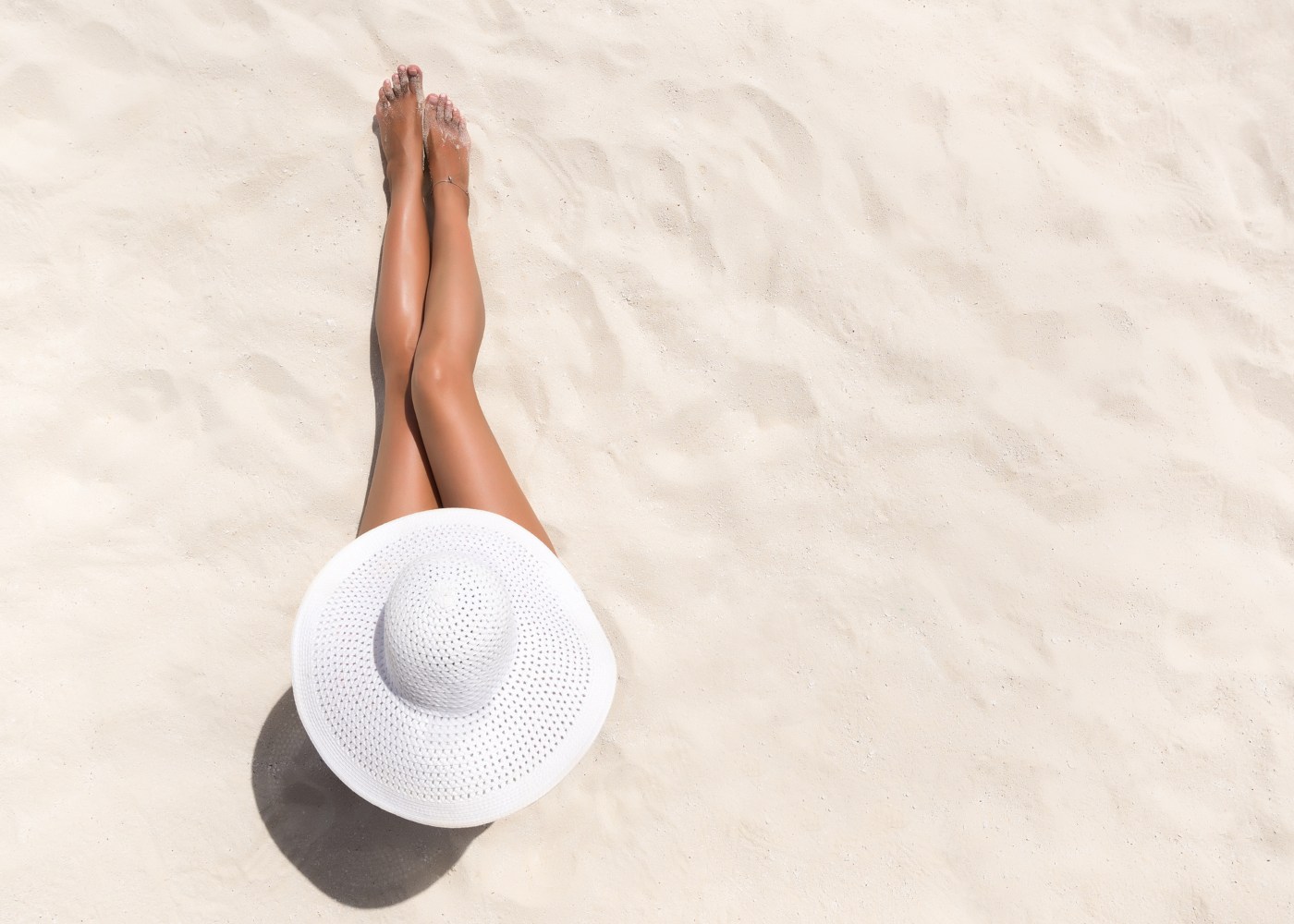 Mulher na praia com pernas bronzeadas