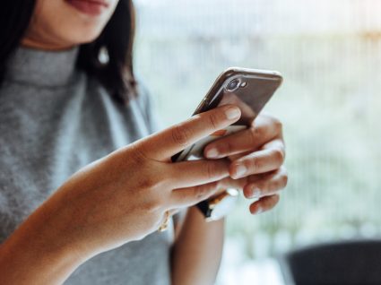 jovem lê notícia no telemóvel sobre fim das comissões bancárias