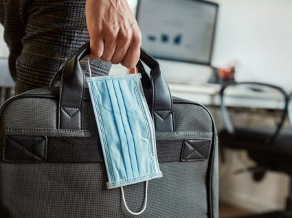 pessoa a segurar pasta de trabalho e máscara de proteção