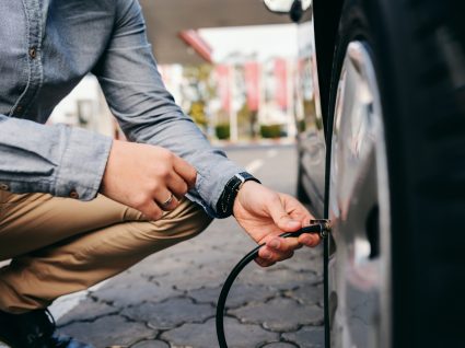 homem a verificar ar dos pneus e preparar o carro para viajar