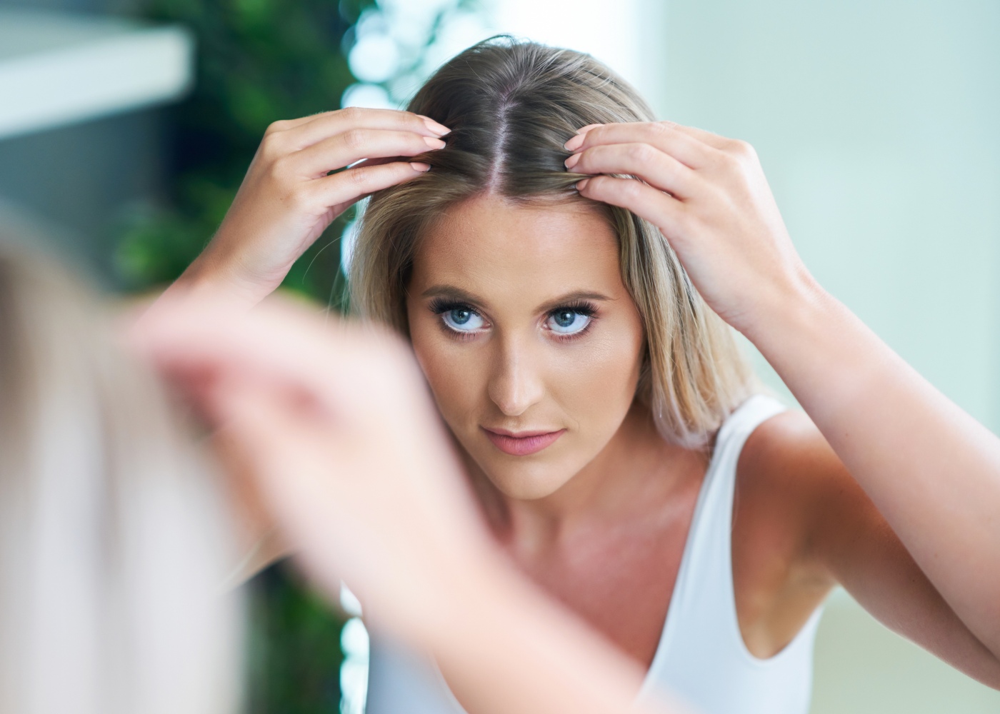 Mulher a inspecionar o cabelo ao espelho