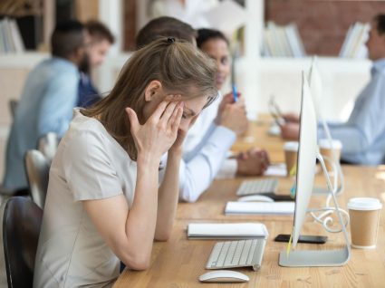 mulher em frente ao computador no escritório com mãos na cabeça em agonia