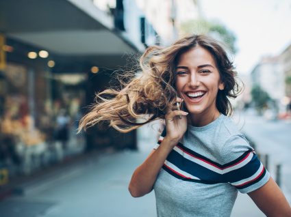 mulher a sorrir com um smartphone a nada rna rua