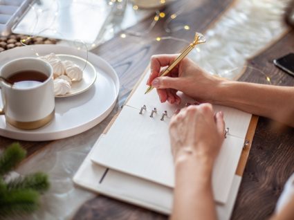 mulher a escrever num caderno as suas resoluções financeiras para o novo ano