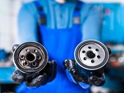 mecânico a mostrar filtro do óleo do carro usado e novo