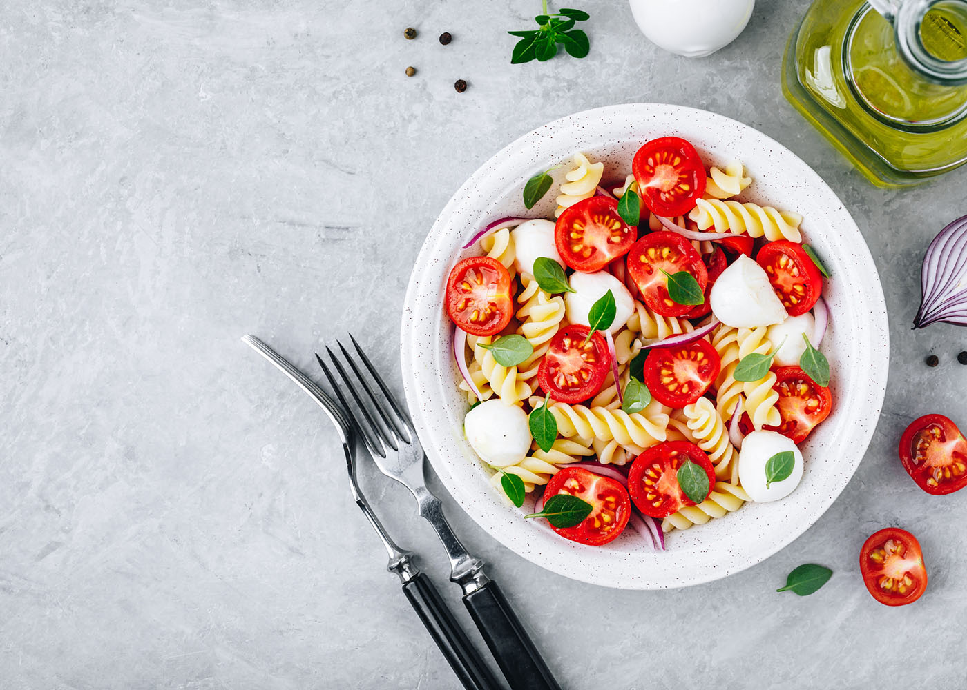 Salada de massa, tomate e mozzarella fresco no prato em fundo cinza