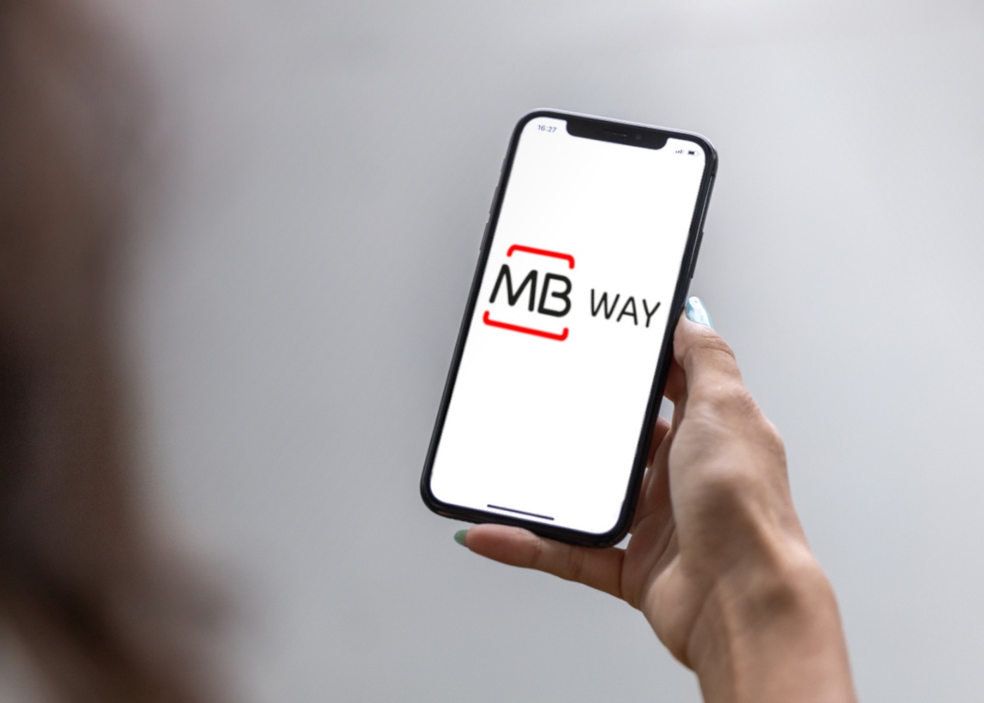 Mulher a segurar telemóvel com MB Way